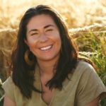 Tara, wearing earth-tone clothing in a field.