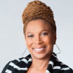 Kimberle Crenshaw in a black and white striped shirt with her hair in a bun, smiling.