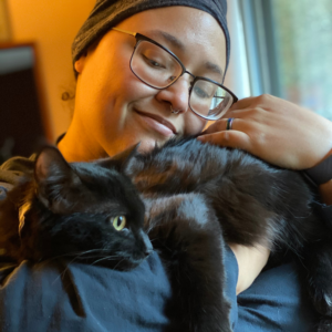 Sara, in glasses, holding a black cat