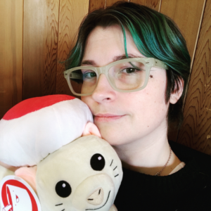 Leah with green hair and clear classes, holding an anime plushie